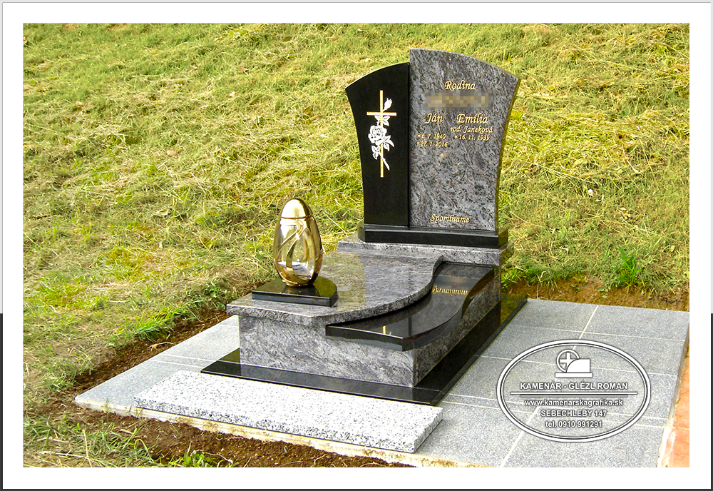Urnový hrob z čiernej a fialovej žuly so zlatým svietnikom a pieskovaným krížom v prírode.